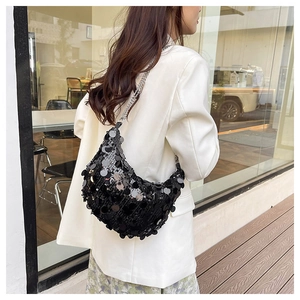 Detailed view of black oversized sequins on a stylish crescent bag with silver chain