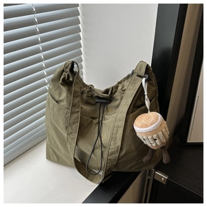 Detail of army green crinkle nylon tote with drawstring closure and plush charm