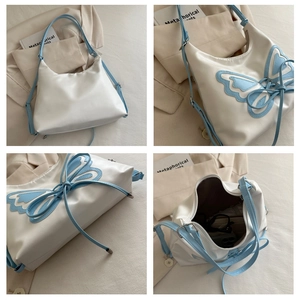 Detalle de bolso media luna marfil con lazo de cinta azul y cierre de cremallera