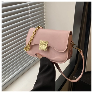 Détail d'un sac bandoulière rose avec fermoir ours doré et bandoulière à chaîne épaisse