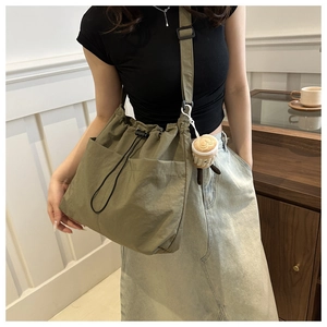 Macro detail of khaki nylon bucket bag showing drawstring closure and plush cup charm