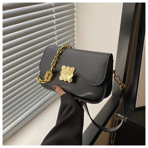 Détail du sac bandoulière noir à bords ondulés, cuir texturé et fermoir doré chic