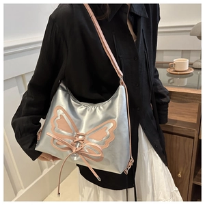 Close-up of silver tote bag featuring pink butterfly patch and lace-up details