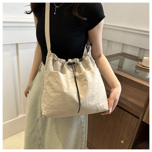 Detalle del bolso tote beige de nylon con cierre de cordón y prácticos bolsillos laterales