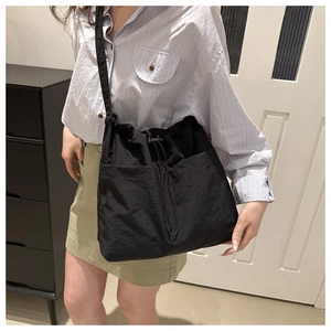 Vista detallada del bolso tote de nylon negro con cordón y bolsillos frontales