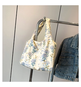 Détail du sac hobo en toile florale avec hortensias bleus suspendu à un cintre