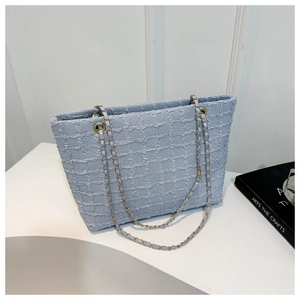Detailed view of light blue tweed tote bag with elegant gold chain shoulder strap