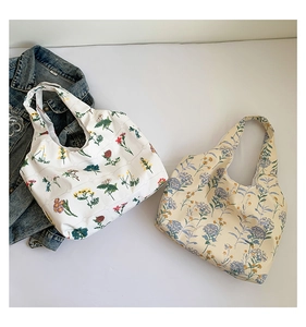Vue à plat de grands sacs fourre-tout en toile à motifs floraux en blanc et jaune