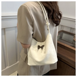 Detalle del bolso de hombro en terciopelo blanco con hebilla de mariposa y correa anudada