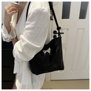 Detalle de bolso cubo negro con hebilla de mariposa plateada y correa con nudos decorativos