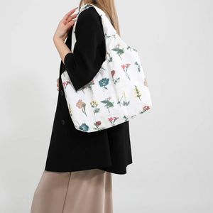 Grand sac cabas en toile blanche avec imprimés floraux porté à l'épaule au quotidien