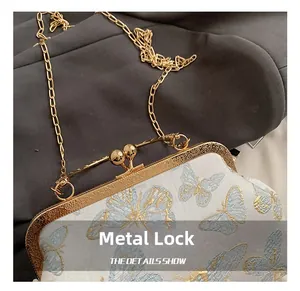 Macro view of hardware clasp and gold chain on floral butterfly embroidery handbag