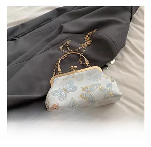 Detail showing the vintage butterfly embroidery and golden metal clasp on the handbag