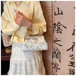 Détail d'un sac à main vintage avec broderie papillon bleu et chaîne en métal doré