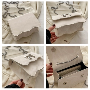 Detail of off-white bow-knot chain bag showing textured leather and wave-edge flap