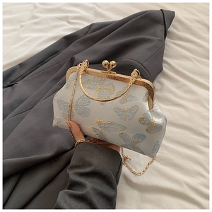 Primer plano del bordado de mariposa azul y dorado en bolso blanco con cadena de metal