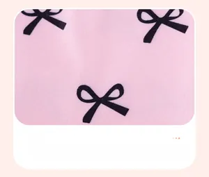 Détail du tissu en coton rose avec motif de nœuds noirs pour vêtements de fille