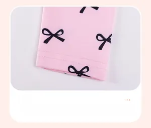 Détail de legging rose pour petite fille avec motifs nœuds noirs et finitions d'ourlet soignées