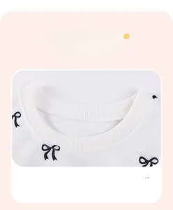 Close-up of ribbed neckline on white long sleeve kids sweatshirt with bow print