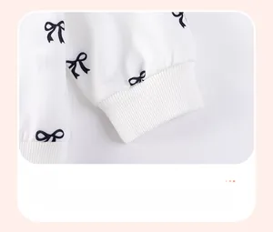 Close-up of white knitted sleeve with ribbed cuffs and delicate black bow patterns