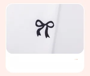 Close-up of white cotton fabric featuring a printed black bow pattern for a girl's outfit