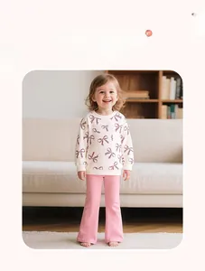 Detail of girl's cotton sweatshirt with leopard bow and pink flared trousers on model