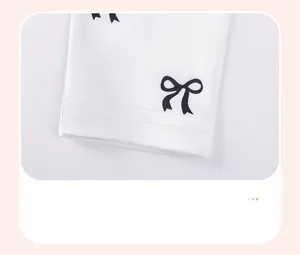 Detail of white cotton girl pants hem featuring black bow print and neat double stitching