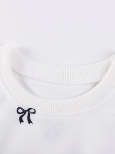White cotton sweatshirt neckline detail with ribbed collar and black bow print