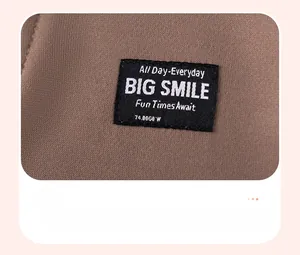 Détail du tricot marron chaud avec une étiquette tissée 'BIG SMILE' noire et texture fine