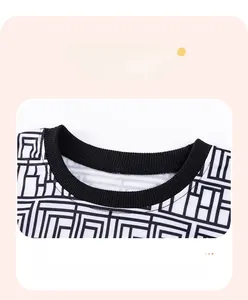 Detail of boys' geometric maze top featuring durable black ribbed crewneck and double stitching
