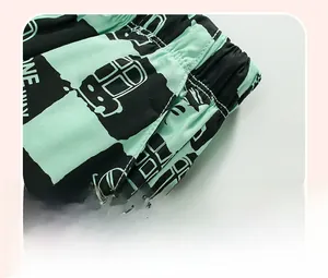 Dettaglio dei pantaloncini in maglia da bambino con scacchi verde menta e stampa bus