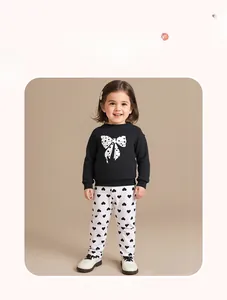 Detail of girl's cotton set featuring a black bow sweatshirt and white heart print pants