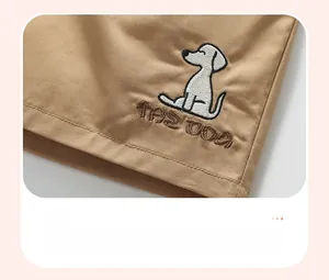 Detailed embroidery of a white puppy and THE DOG text on khaki cotton fabric