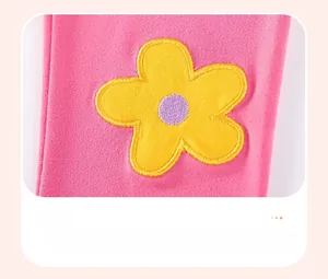 Dettaglio ricamo floreale giallo su completo autunnale rosa a maniche lunghe bimba