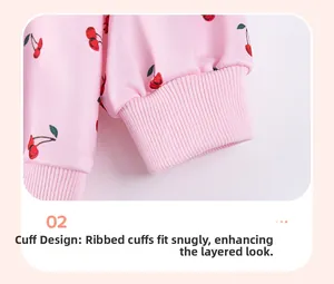 Detail of baby girl outfit showing the pink ribbed cuffs and red cherry pattern print