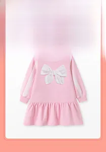 Détail d'une robe rose à manches longues en coton avec un grand nœud blanc 3D et volants