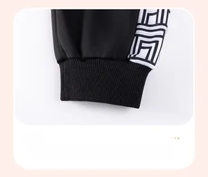 Detail of ribbed cuffs on black knit trousers with geometric side patterns for boys