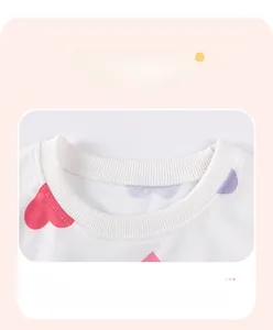 Close-up of girls' white rib knit crewneck with reinforced stitching and heart print