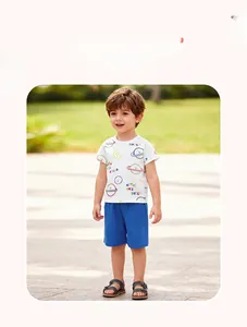 Outdoor shot of a boy wearing a white cotton planet print T-shirt and blue shorts set