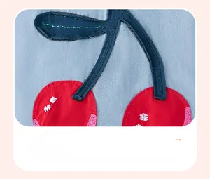 Detail of red cherry applique embroidery on light blue denim sleeveless dress