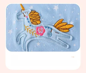 Gros plan d'une broderie licorne appliquée sur une robe d'été bleue à motif étoiles