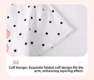 Détail de robe bébé à pois blancs montrant la texture coton et la finition des manches