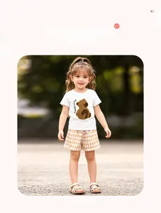 Détail d'un t-shirt blanc pour fille avec motif ours et short d'été à carreaux