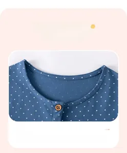 Détail du col d'une robe bleue à pois en coton avec encolure ronde et petit bouton en bois