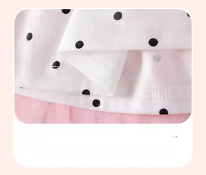 Détail du tricot blanc à pois et ourlet en tulle rose avec couture fine de robe