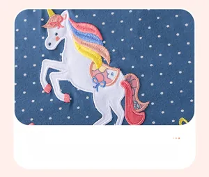 Détail de la broderie licorne colorée sur tissu bleu à pois pour robes de petites filles
