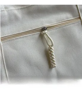Detailed macro view of high-quality zipper and woven puller on cream canvas tote bag