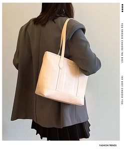 Beige tote bag with vertical water ripple texture shown on model in a minimalist setting