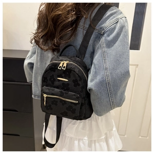 Vue détaillée d'un mini sac à dos noir avec motifs floraux et fermeture dorée portée