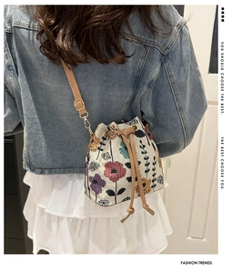Macro detail of ethnic floral jacquard bucket bag with brown leather drawstring straps
